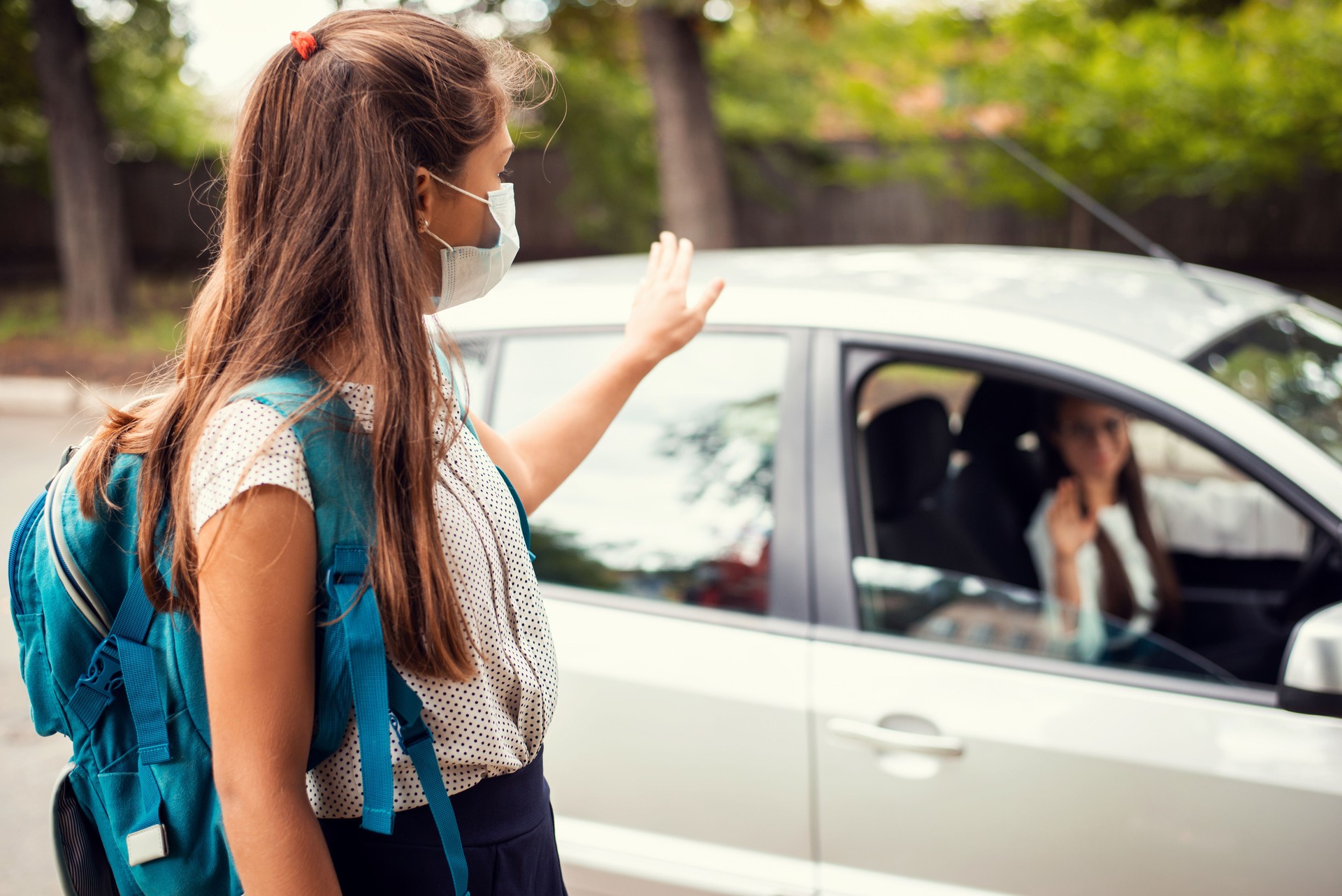 Mutter im Auto, die ihre Tochter zur Schule absetzte und ihr einen guten Tag wünschte. Zurück zur Schule, Mutterschaftskonzept.